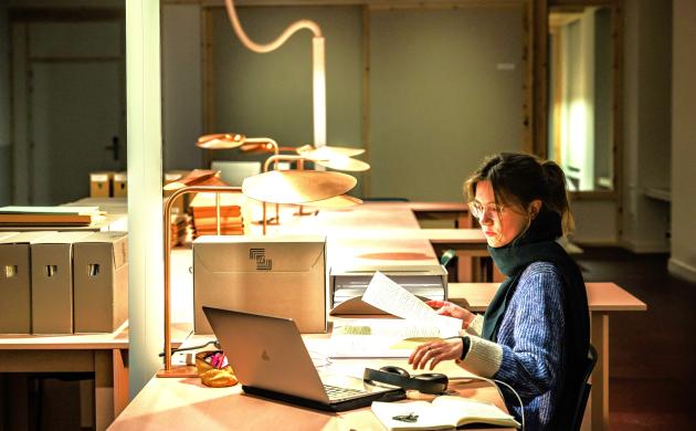 Studente in de weer met archiefstukken in de leeszaal