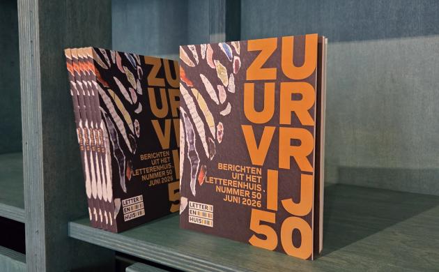 Enkele exemplaren van Zuurvrij 50 in een boekenkast, waarvan één met de cover naar voor gericht